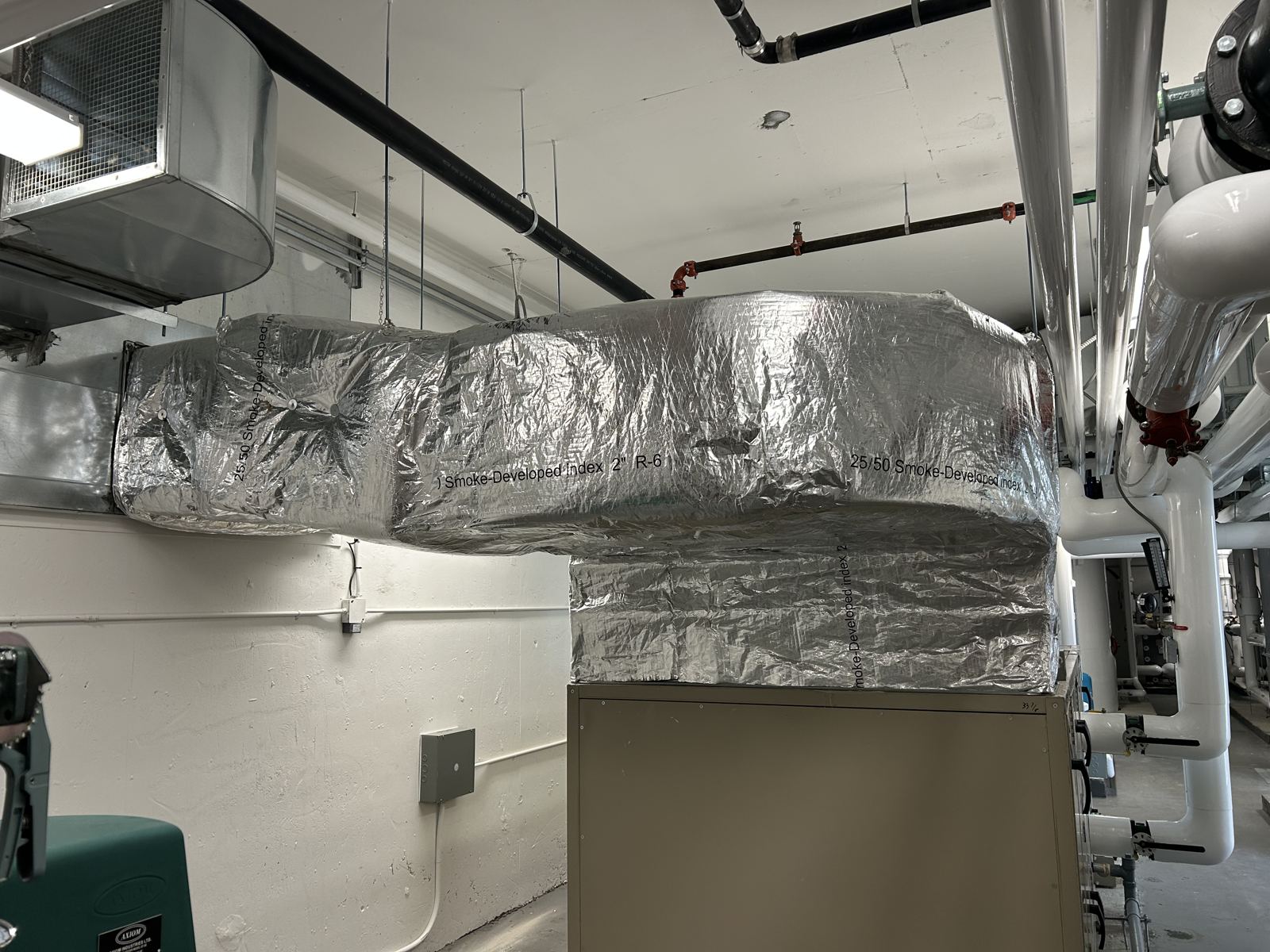 Interior supply duct wrapped in foil-faced insulation along a ceiling