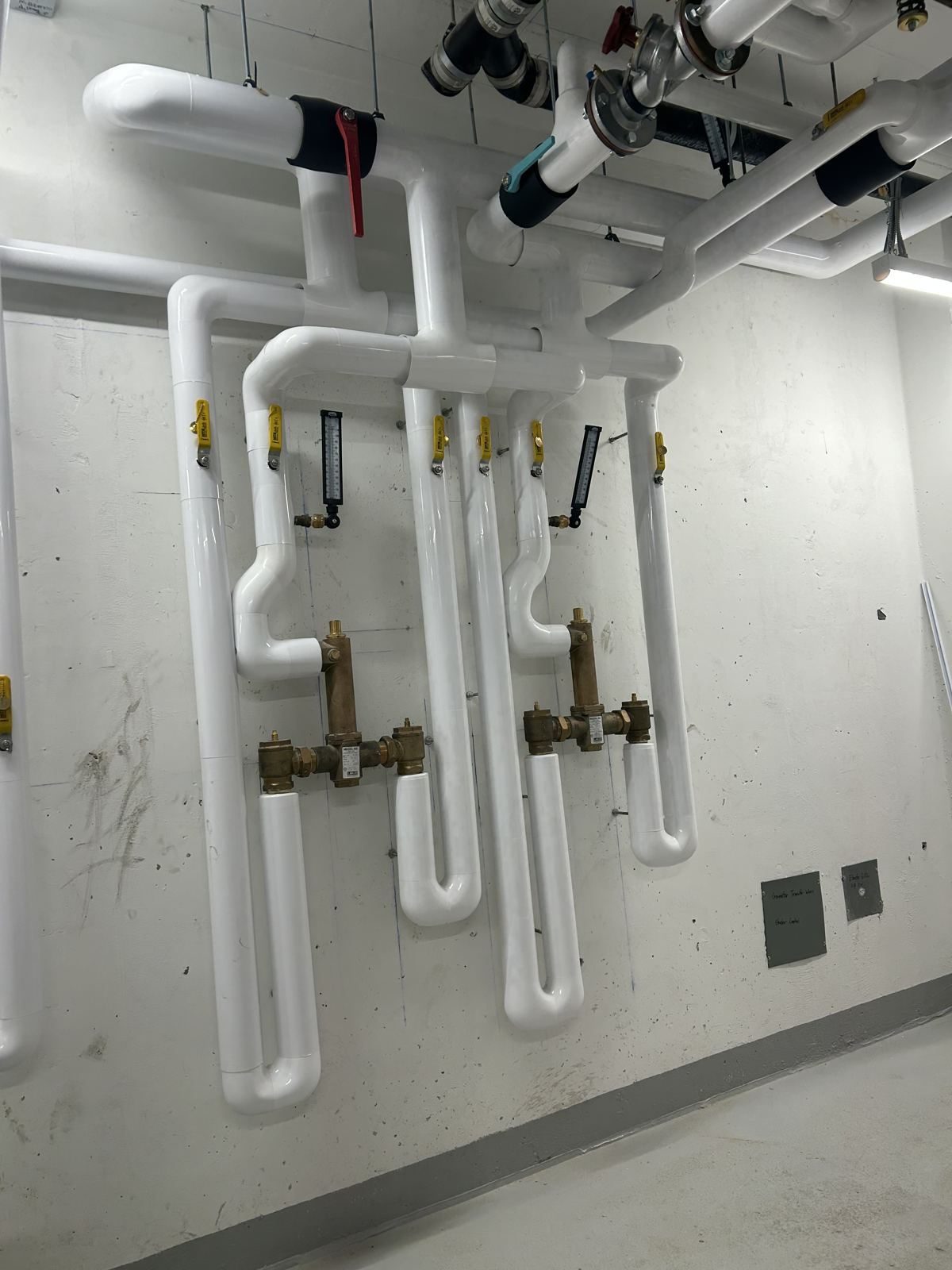Insulated manifolds and balancing valves on a mechanical room wall